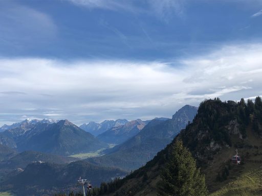 Berglandschaft mit hohen Gipfeln und grauem Himmel über einem grünen Tal.