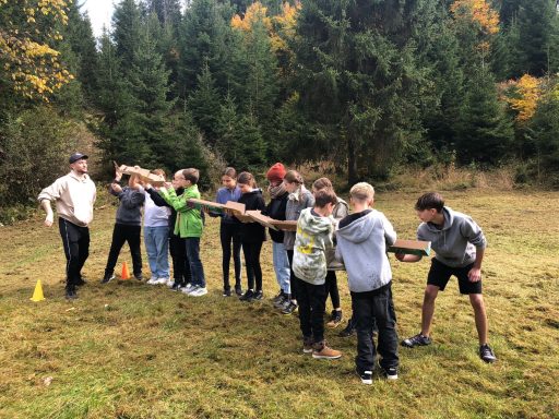 Gruppe von Kindern im Freien, die eine Teamübung in der Natur durchführen.