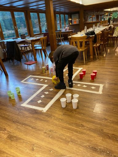 Junge spielt ein Spiel auf dem Boden mit bunten Bechern in einem Restaurant.