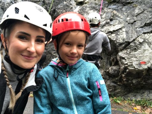 Frau und Mädchen in Kletterausrüstung, Felsen im Hintergrund, Outdoor-Aktivität.